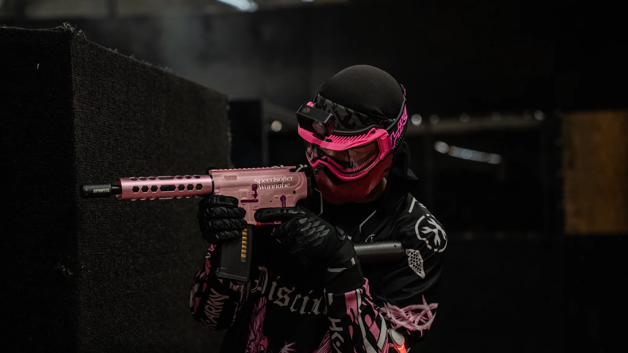 Disciples Airsoft player aiming a pink airsoft replica from cover