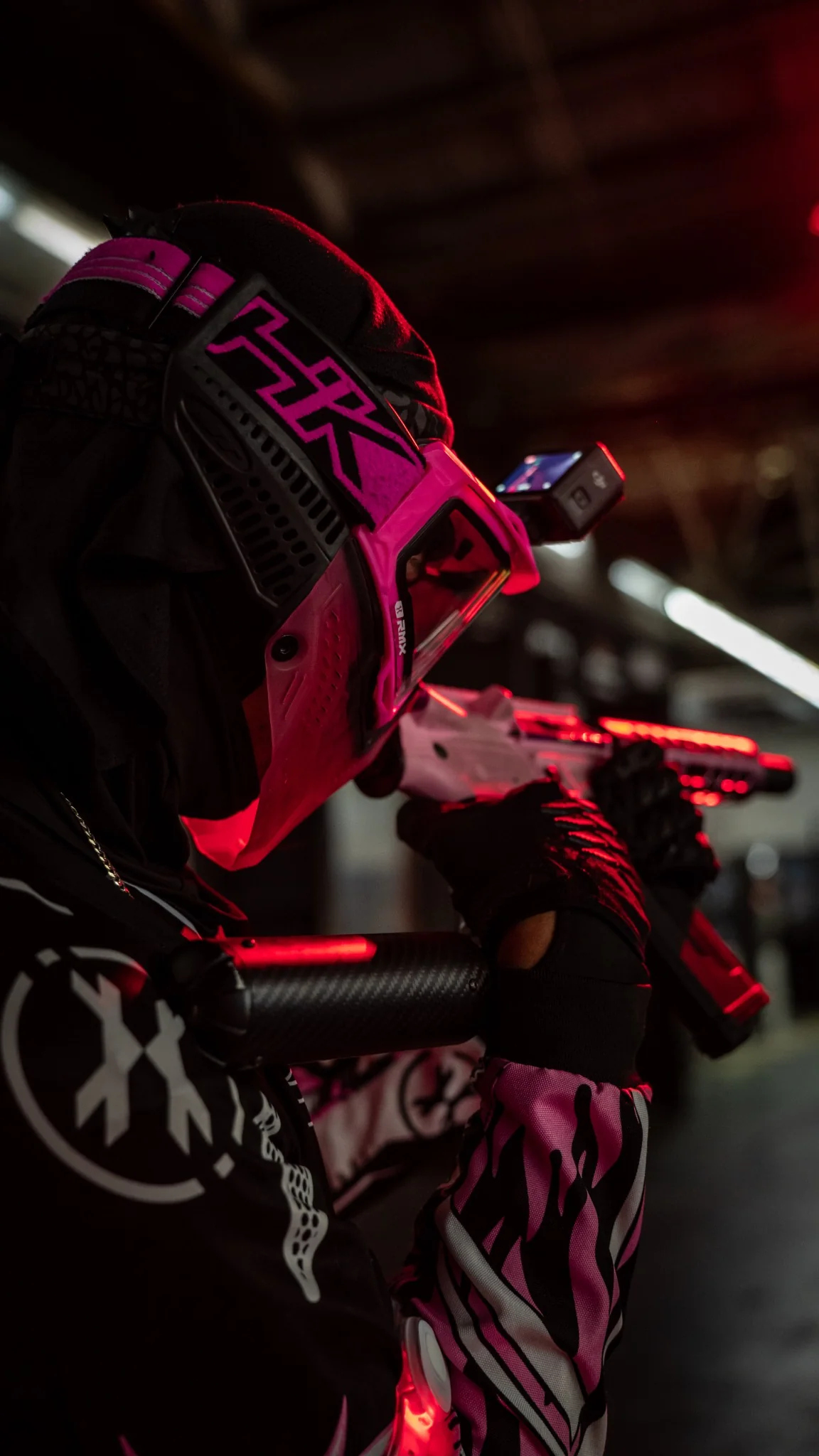 Close-up of a Disciples Airsoft player in a hot-pink mask under red field lighting