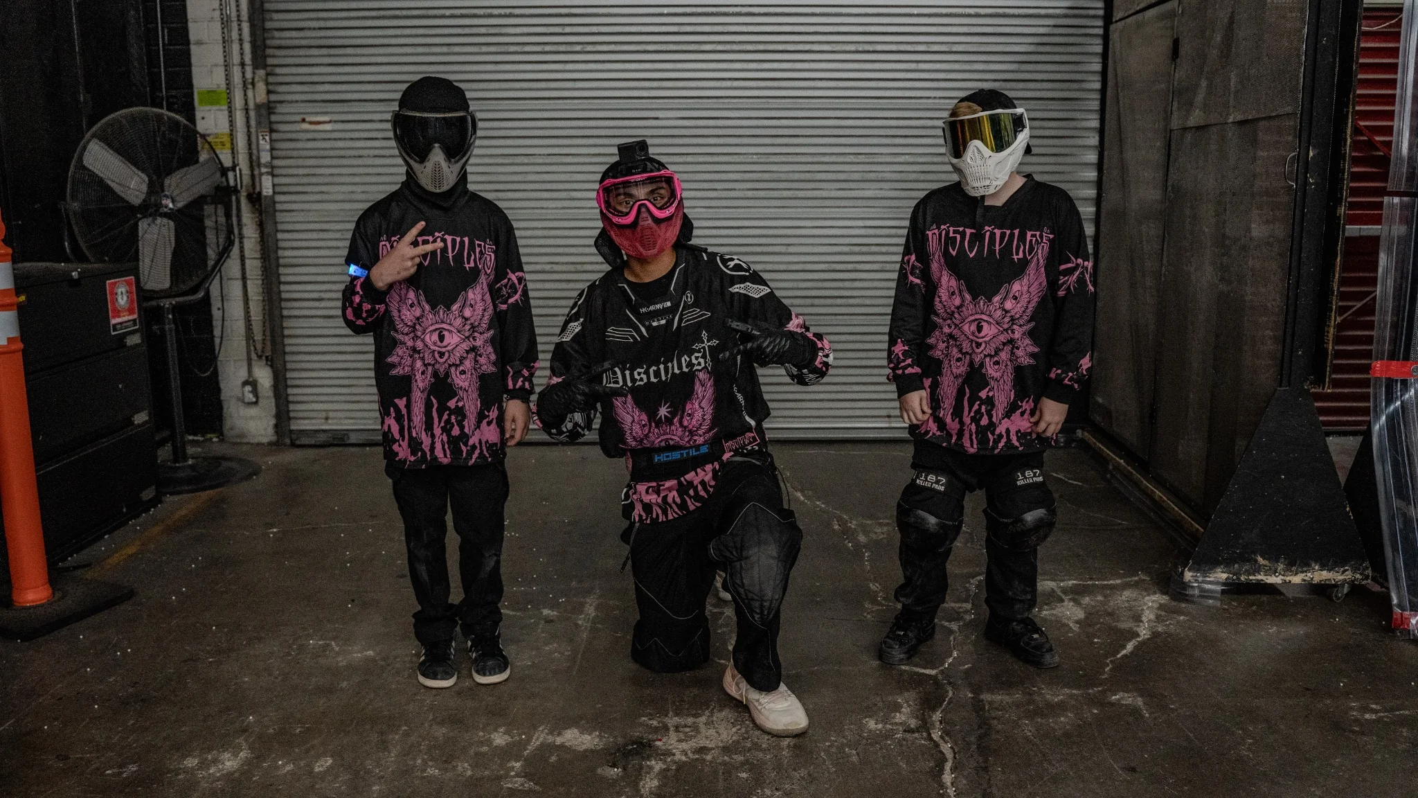 Three Disciples Airsoft players wearing black and hot-pink jerseys at an indoor field